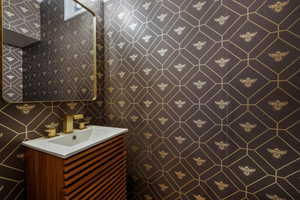 Half bathroom featuring vanity and tile walls