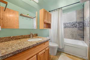 Bathroom with shower / bathtub combination with curtain, vanity, and light tile patterned flooring