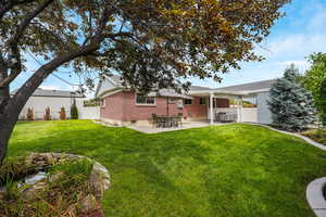 Back of property with a patio area, brick siding, and a shingled roof