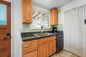 Kitchen featuring backsplash, dark countertops, and black dishwasher