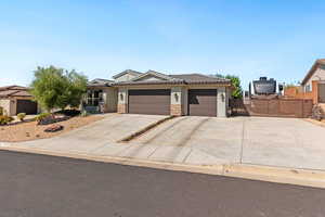 View of front of property featuring an attached garage, driveway, stone siding, and a gate