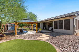 Rear view of house featuring a gazebo, a patio area, a ceiling fan, a tiled roof, and stucco siding