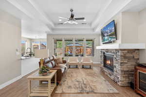Living area with light wood-style floors, a fireplace, ceiling fan, and healthy amount of natural light