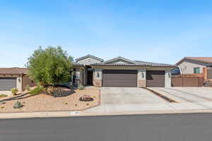 View of front of property with an attached garage, concrete driveway, stone siding, and stucco siding