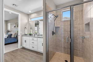 Ensuite bathroom featuring light wood-type flooring, double vanity, a stall shower, and recessed lighting