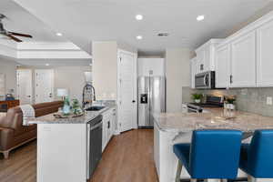 Kitchen with a peninsula, a breakfast bar, open floor plan, light stone countertops, and appliances with stainless steel finishes