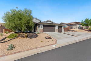 View of front facade with a garage, driveway, a tiled roof, stucco siding, and stone siding