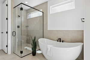 Full bath with a soaking tub, a shower stall, tile walls, and tile patterned flooring
