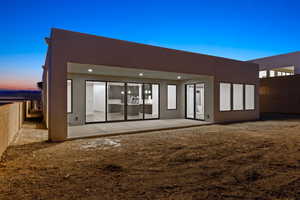 Back of property with stucco siding and a patio