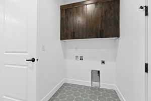Washroom with hookup for a washing machine, cabinet space, hookup for an electric dryer, and light tile patterned floors