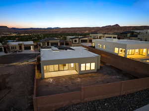 Back of house at dusk with a patio area, a mountain view, and a residential view