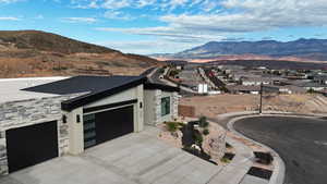 View of front of property featuring stone siding, a mountain view, driveway, a garage, and a residential view
