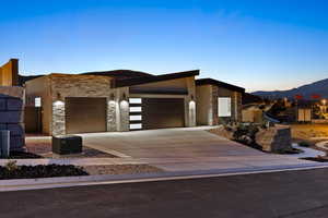 Modern home with stone siding, a garage, driveway, and a mountain view