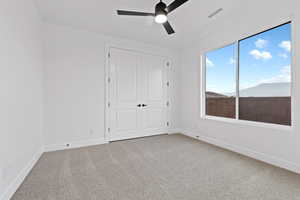 Unfurnished bedroom with light carpet, ceiling fan, and a closet
