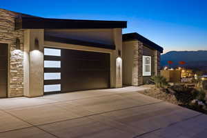 View of front of house featuring stone siding, a mountain view, concrete driveway, and stucco siding