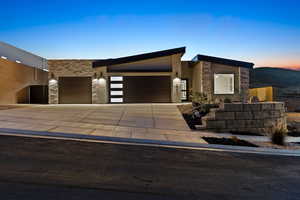 Contemporary home featuring stone siding, an attached garage, concrete driveway, and stucco siding
