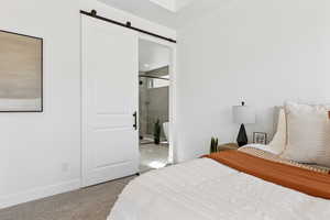 Carpeted bedroom with a barn door and ensuite bathroom
