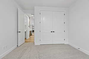 Unfurnished bedroom featuring light colored carpet and a closet