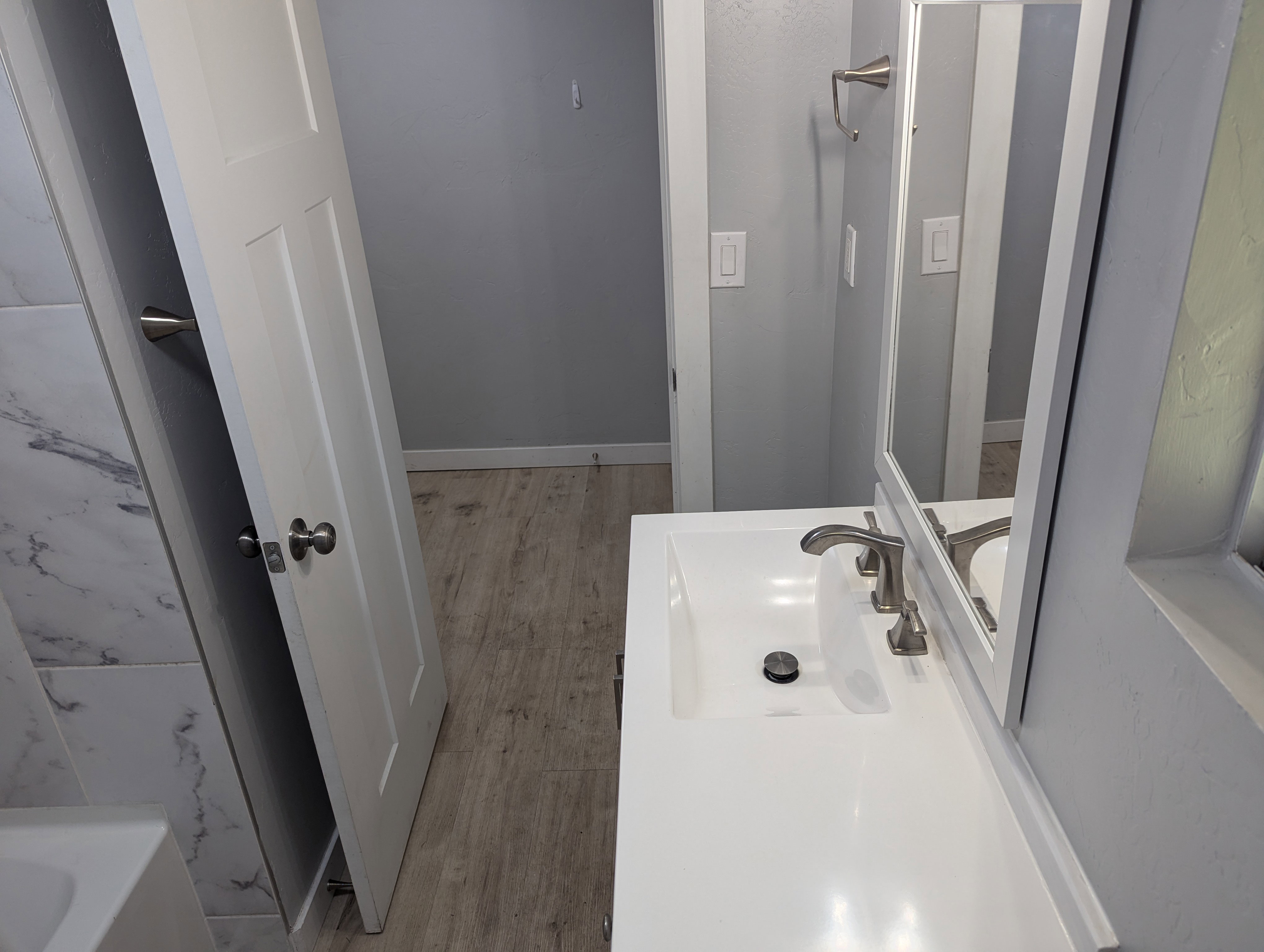 Full bath with vanity, a tub to relax in, and light wood-style flooring