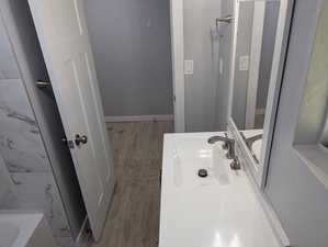 Full bath with vanity, a tub to relax in, and light wood-style flooring
