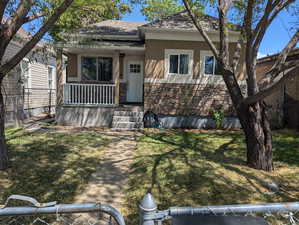 View of front of property featuring stucco siding, a porch, roof with shingles, and stone siding