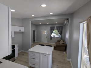 Kitchen featuring white cabinetry, recessed lighting, open floor plan, light wood-type flooring, and stainless steel range oven