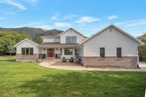 View of front of property with covered porch, brick siding, a front yard, and a mountain view