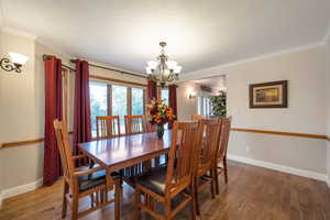 Dining room featuring crown molding, wood finished floors, and a chandelier