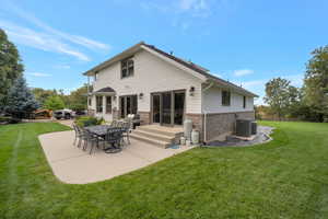 Back of house featuring brick siding, a patio area, and a lawn