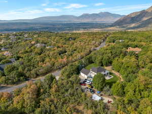 Aerial view of property and surrounding area with a forest and a mountainous background