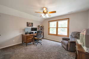 Carpeted office with lofted ceiling and a ceiling fan