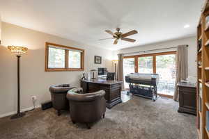 Office space featuring dark carpet and a ceiling fan