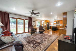 Living room featuring light wood-type flooring, ceiling fan, a chandelier, and recessed lighting