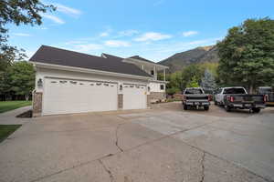 View of side of home with brick siding, driveway, a shingled roof, and a mountain view