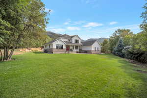 View of front of home with a mountain view, brick siding, a front lawn, and a porch