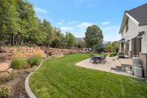 View of green lawn with a patio and a mountain view