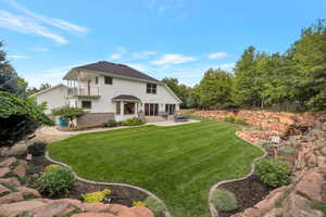 Rear view of property with a patio area, a lawn, brick siding, and a balcony