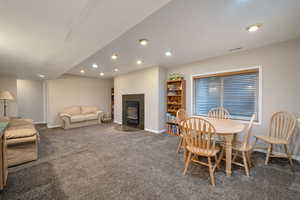 Carpeted dining room with a fireplace with flush hearth and recessed lighting