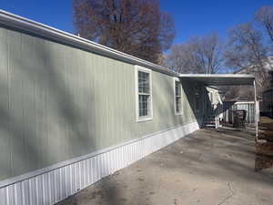 View of property exterior with an attached carport and concrete driveway