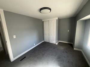 Unfurnished bedroom with dark carpet and a closet