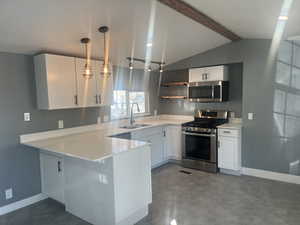 Kitchen with white cabinets, stainless steel appliances, a peninsula, and hanging light fixtures