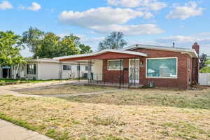 Single story home featuring covered porch, brick siding, a chimney, and a front lawn
