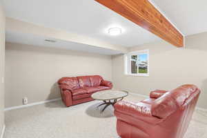 Living area with beamed ceiling and carpet