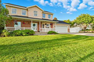 View of front of home featuring a porch, a front lawn, concrete driveway, stucco siding, and brick siding