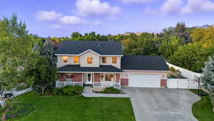 Traditional home with covered porch, a gate, a shingled roof, driveway, and brick siding