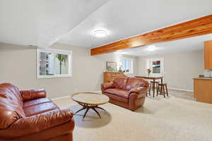 Living area featuring beam ceiling and light colored carpet