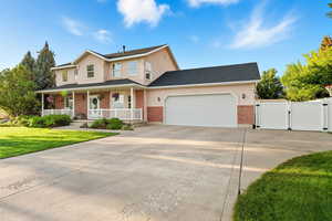 View of front of house with a gate, covered porch, concrete driveway, a front yard, and a garage