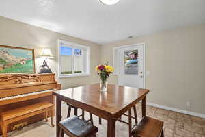 Dining area featuring healthy amount of natural light, a textured ceiling, and light stone finish flooring