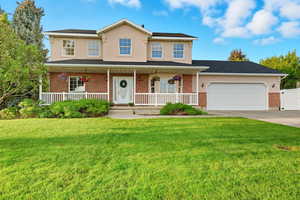 View of front of property featuring covered porch, a front yard, driveway, and stucco siding