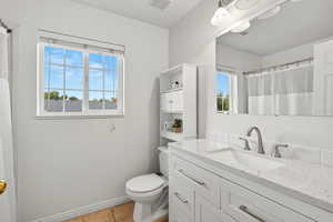Full bath with light tile patterned floors, vanity, and a shower with shower curtain